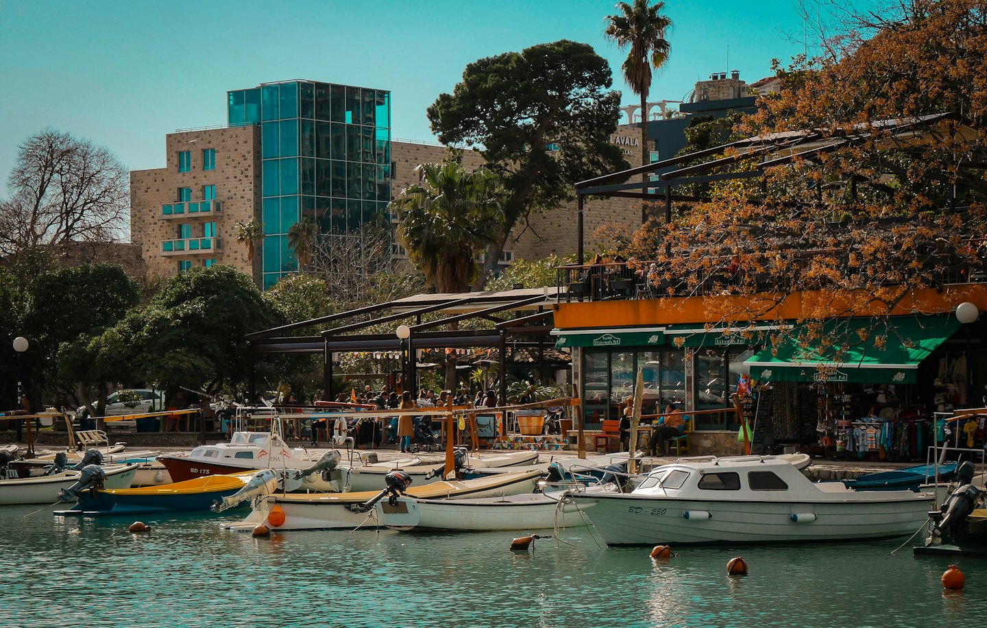 Boats docked at a waterfront marina with shops and restaurants.