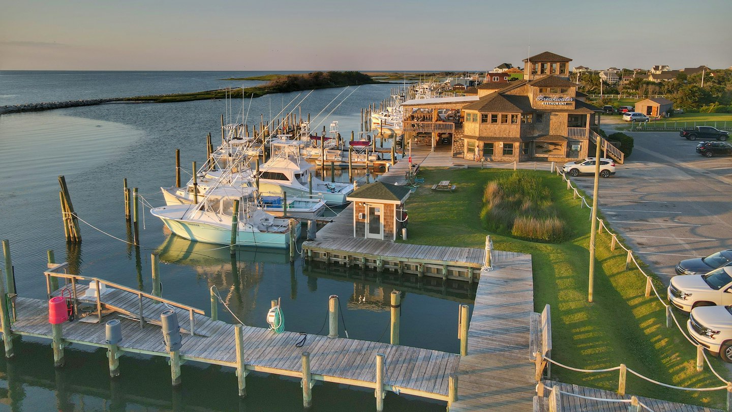 Fishing boats docked at a marina beside a coastal restaurant.
